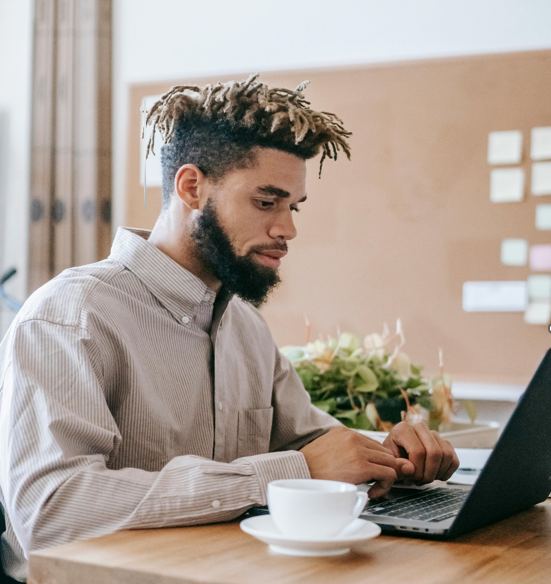 Young man sitting at desk infront of laptop computer.